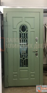 оливковая входная дверь с арочным остеклением и изящной кованой решеткой